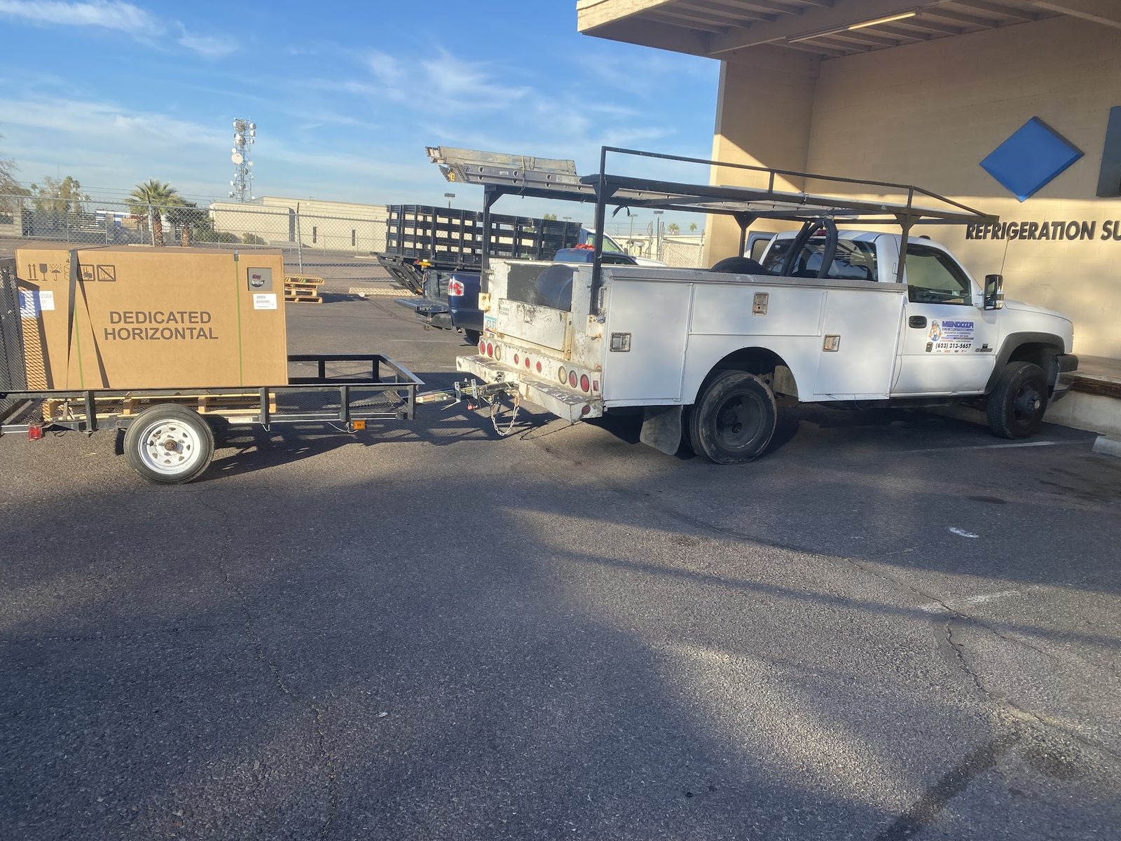 The Mendoza service truck and trailer collecting a boxed air handler from a refrigeration supply house.